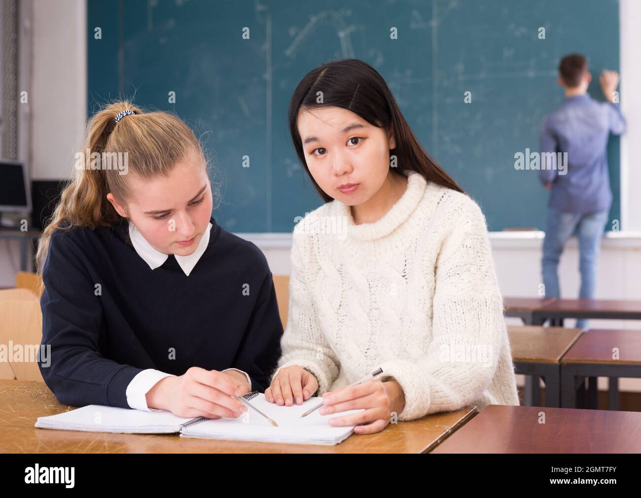 Tired female students during writing notes in classroom Stock Photo