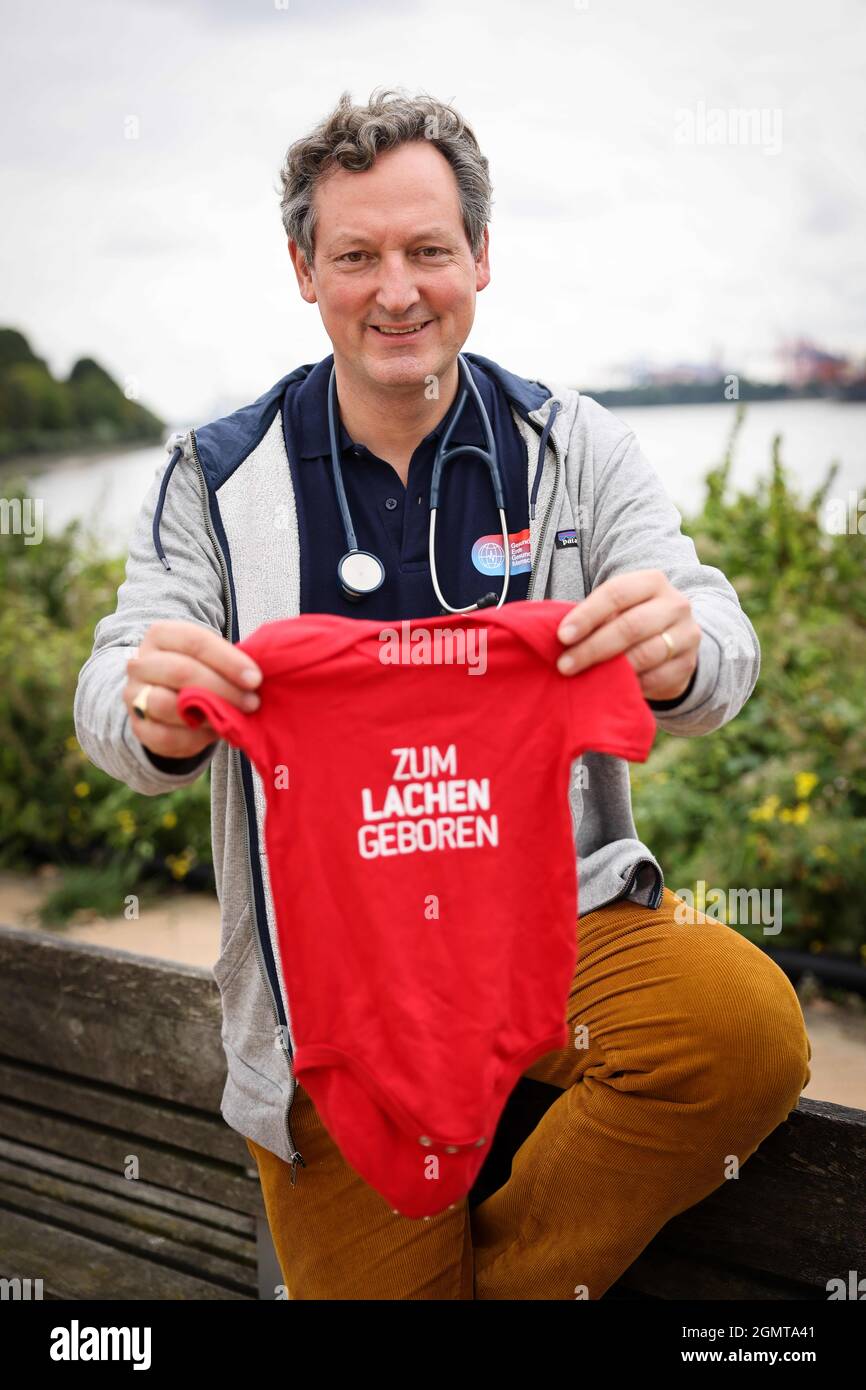 Hamburg, Germany. 20th Sep, 2021. Eckart von Hirschhausen, doctor and  science journalist, holds a red romper suit with the text "Zum Lachen  Geboren" ("Born to Laugh") at a photo opportunity on the