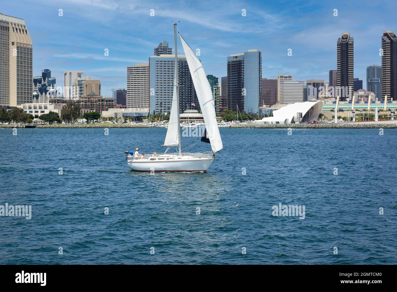 A sailboat glides across the San Diego bay before the waterfront marina district with the Hyatt and Marriott Hotels dominating the San Diego skyline Stock Photo