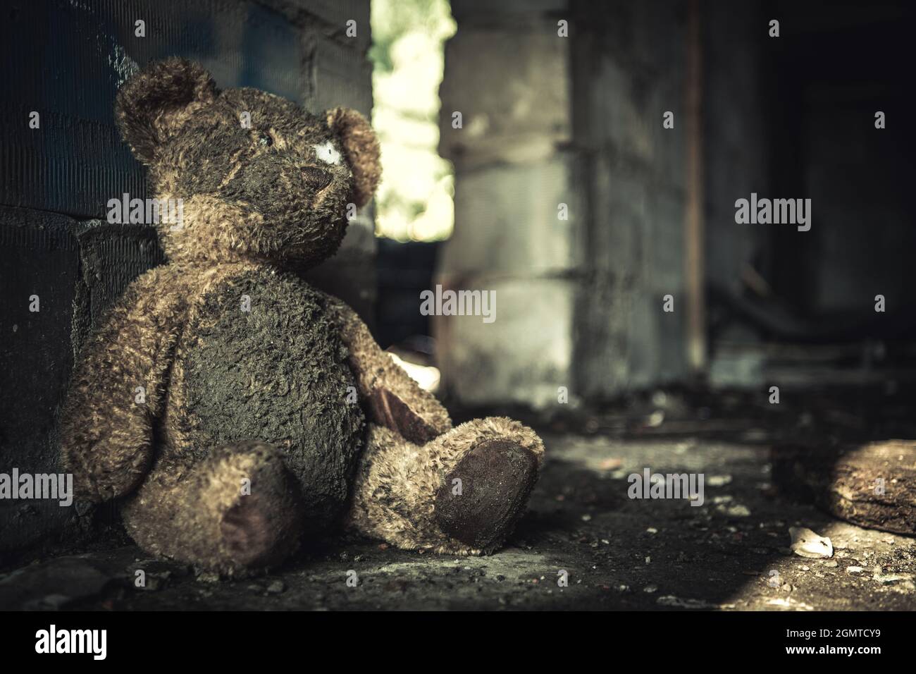 Domestic Violence or Abuse Theme with Dirty Teddy Bear Inside House Ruins. Stock Photo