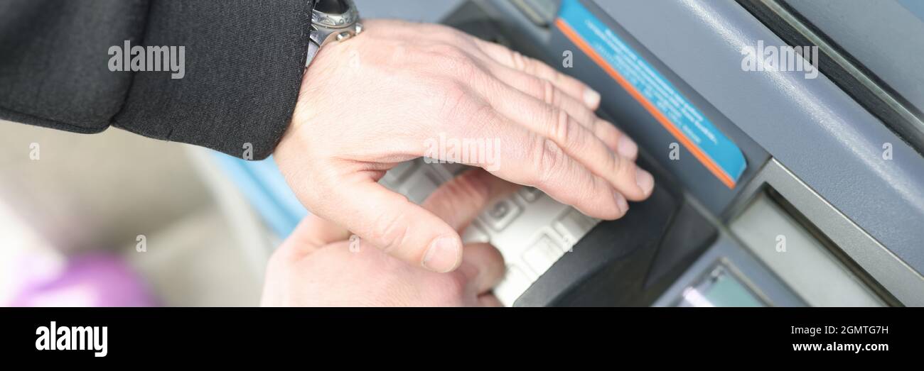 Man enters code on ATM keyboard and closes it with his hand Stock Photo