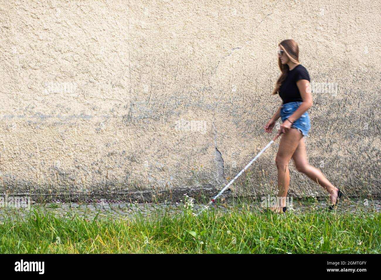 Blind woman walking on city streets, using her white cane to navigate the  urban space better and to get to her destination safely Stock Photo - Alamy