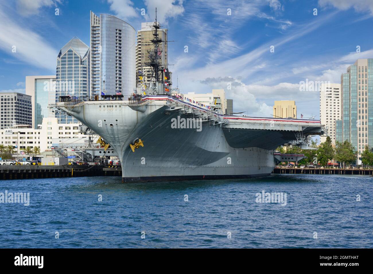 The USS Midway, the historical aircraft carrier battleship, now a museum,  at the San Diego Harbor with downtown San Diego skyline in background Stock Photo