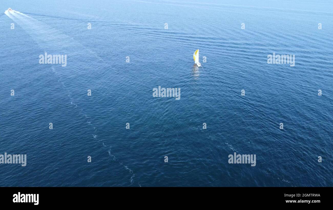 A sailing boat sails into the open sea. Aerial drone from a bird's eye ...