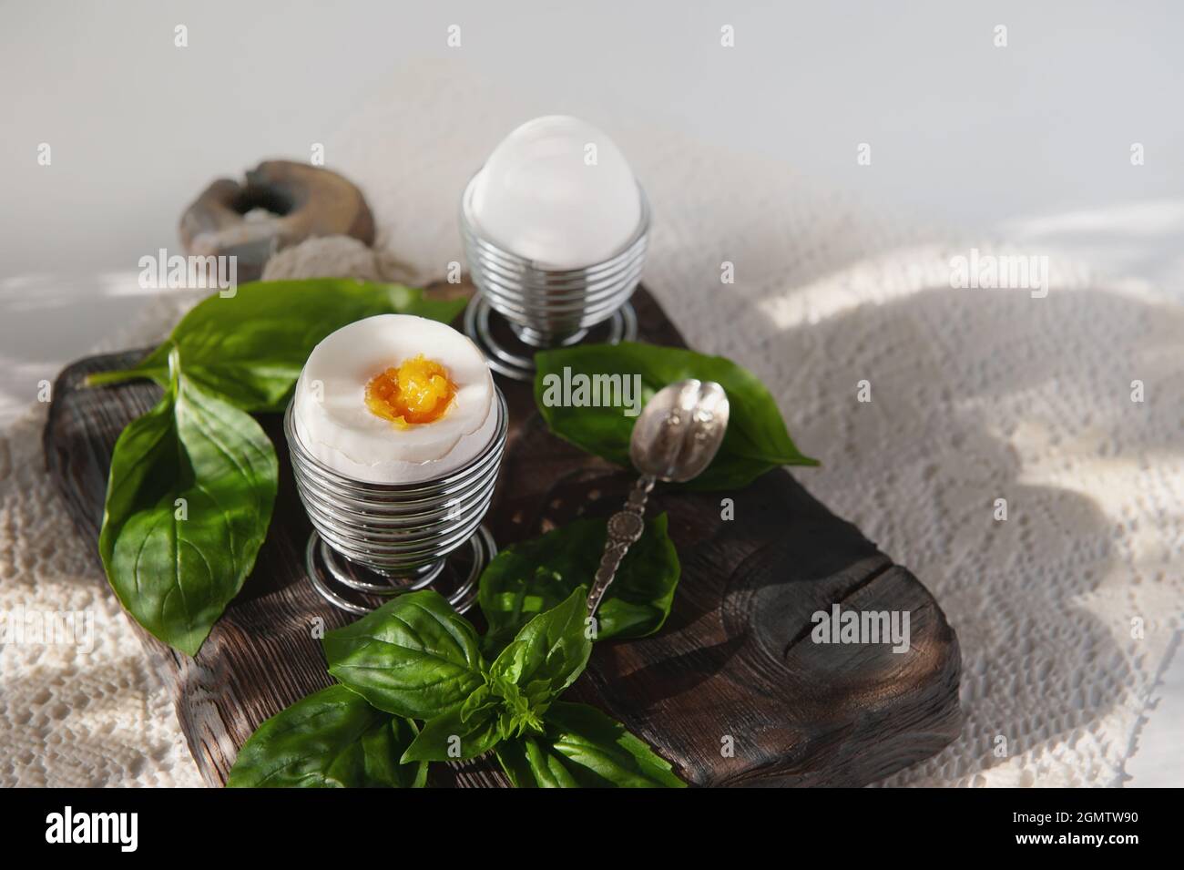 Open a soft-boiled egg in an egg cup. Homemade low-calorie breakfast with a spoon on a rustic table. copy space. Stock Photo