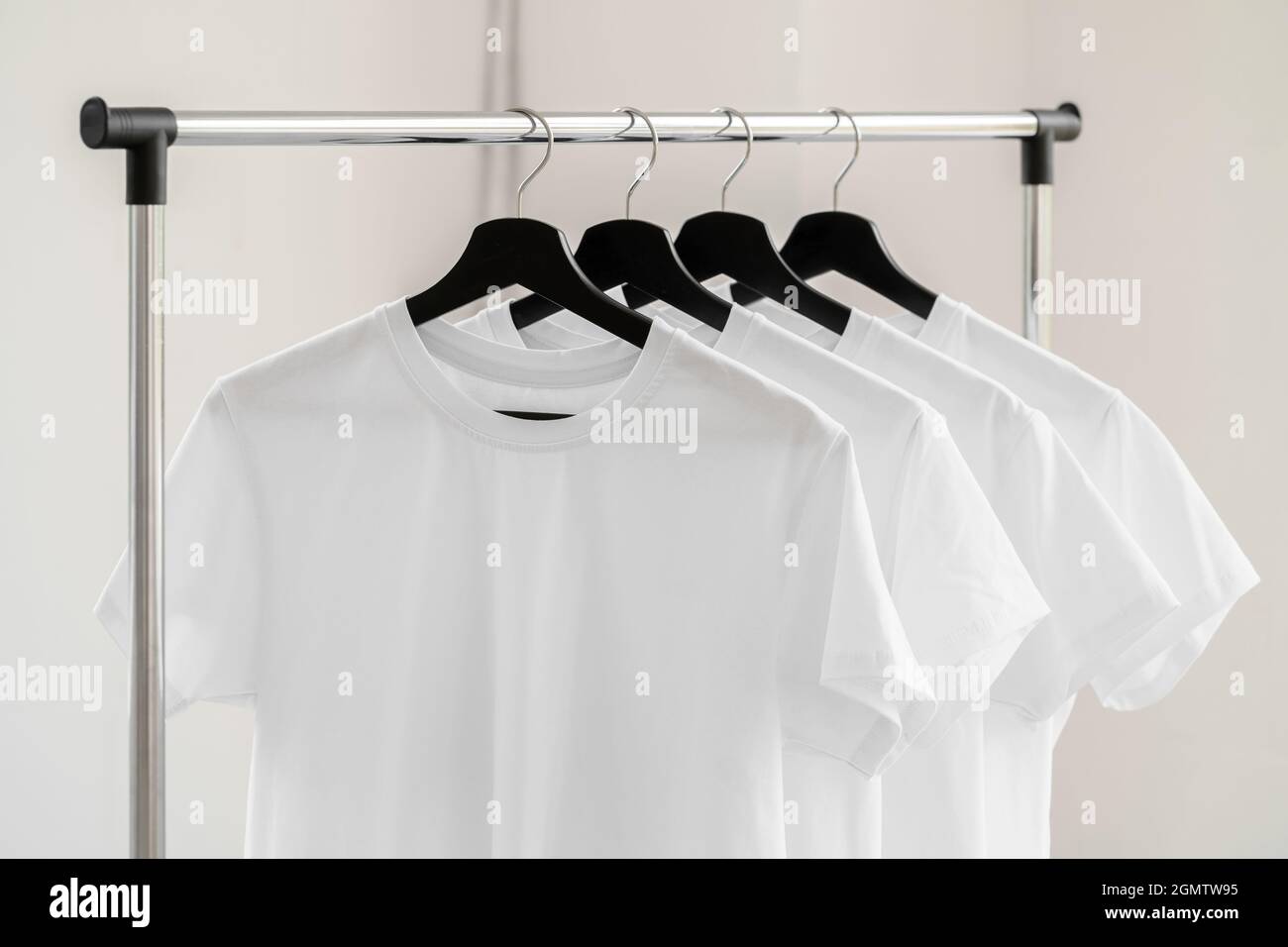 Row of white t-shirts on hangers on rack Stock Photo - Alamy