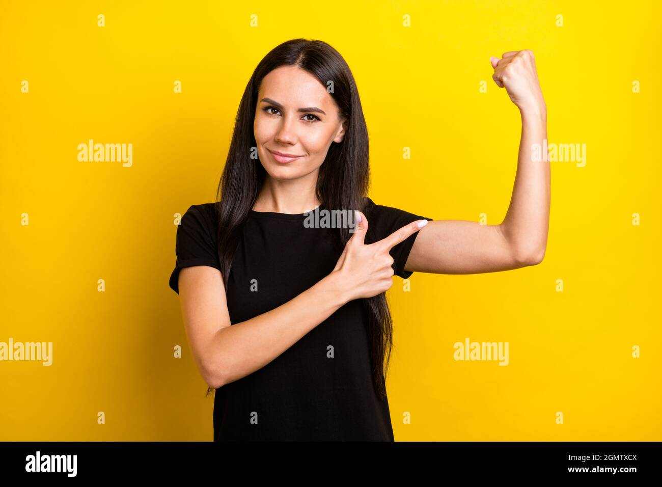 Portrait of charming positive girl indicate finger hand flex show biceps isolated on yellow color background Stock Photo