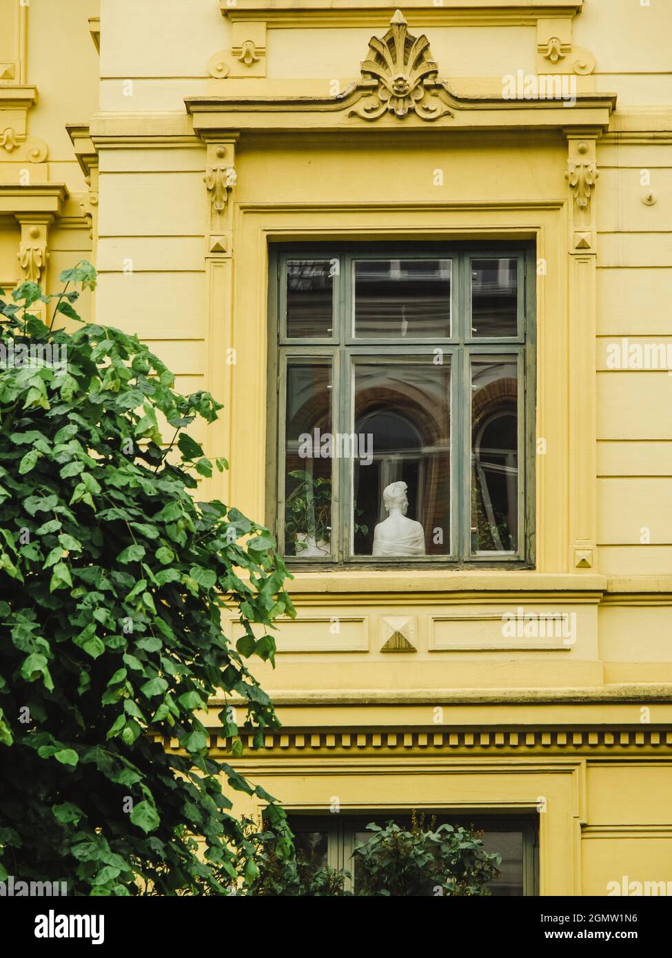 marble bust in the window of old european building. marble bust the goddess with her head turned out from the window, view from outside of building Stock Photo