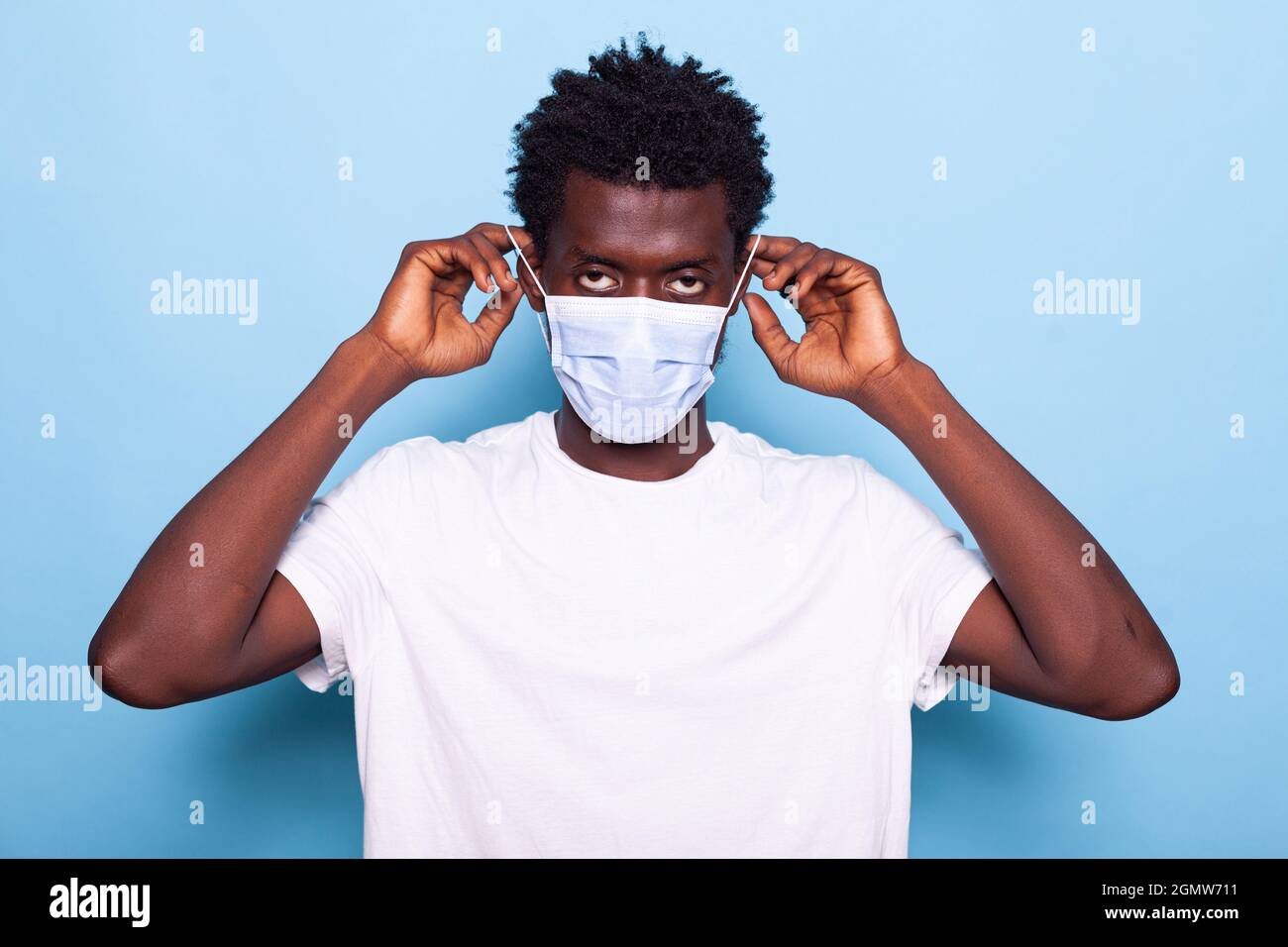 Portrait of casual man using hands to put face mask on face for