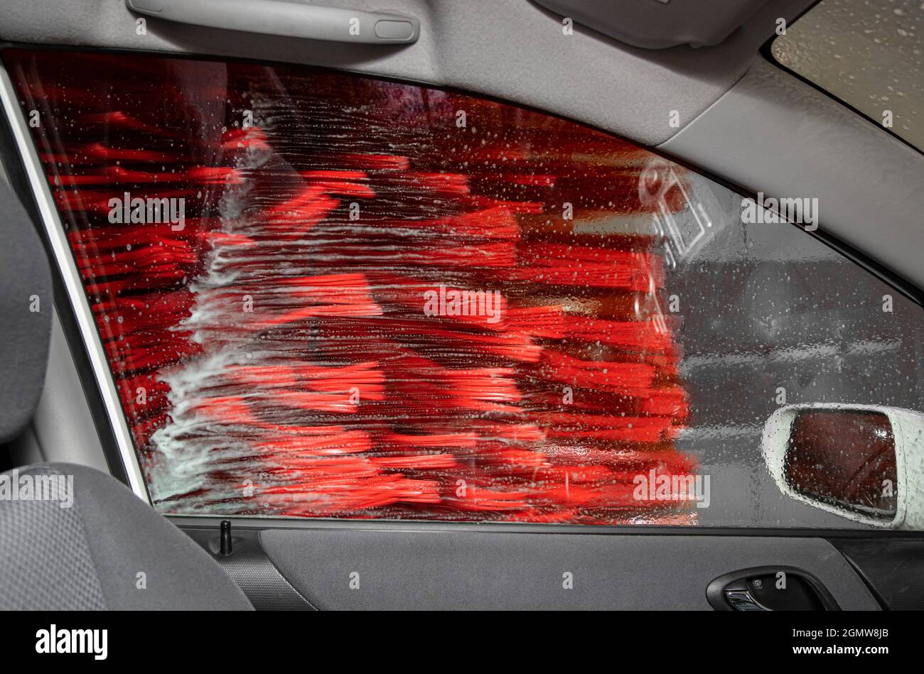 Looking out the passenger window inside automate car wash service, brushes are spinning and cleaning the car. Car wash concept. Stock Photo