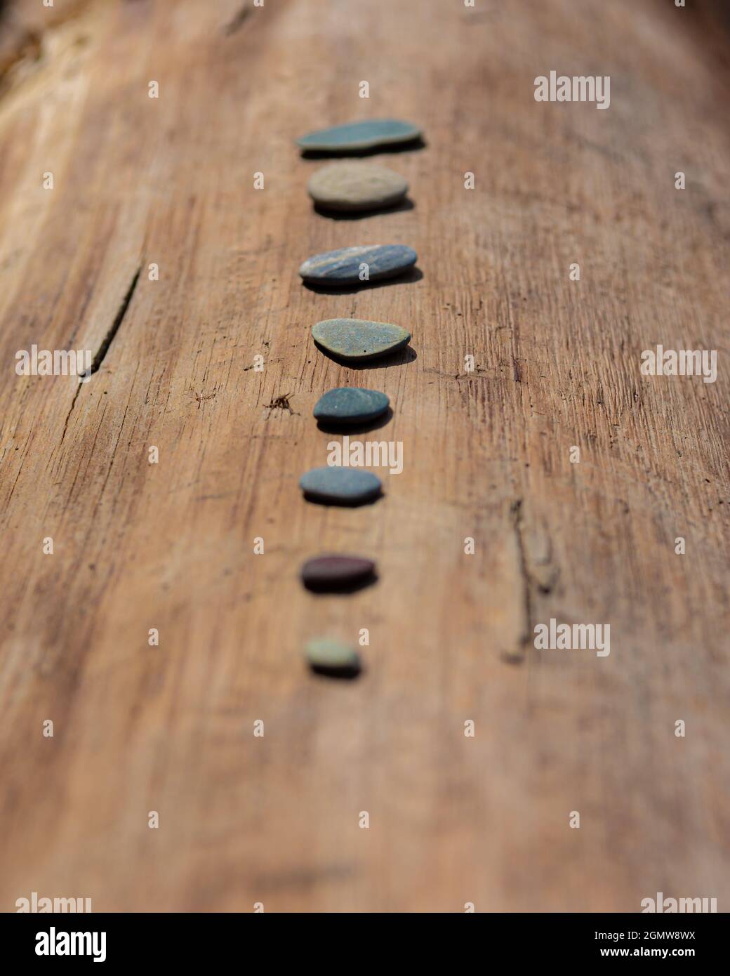 colored small flat rocks on the wooden beam Stock Photo - Alamy