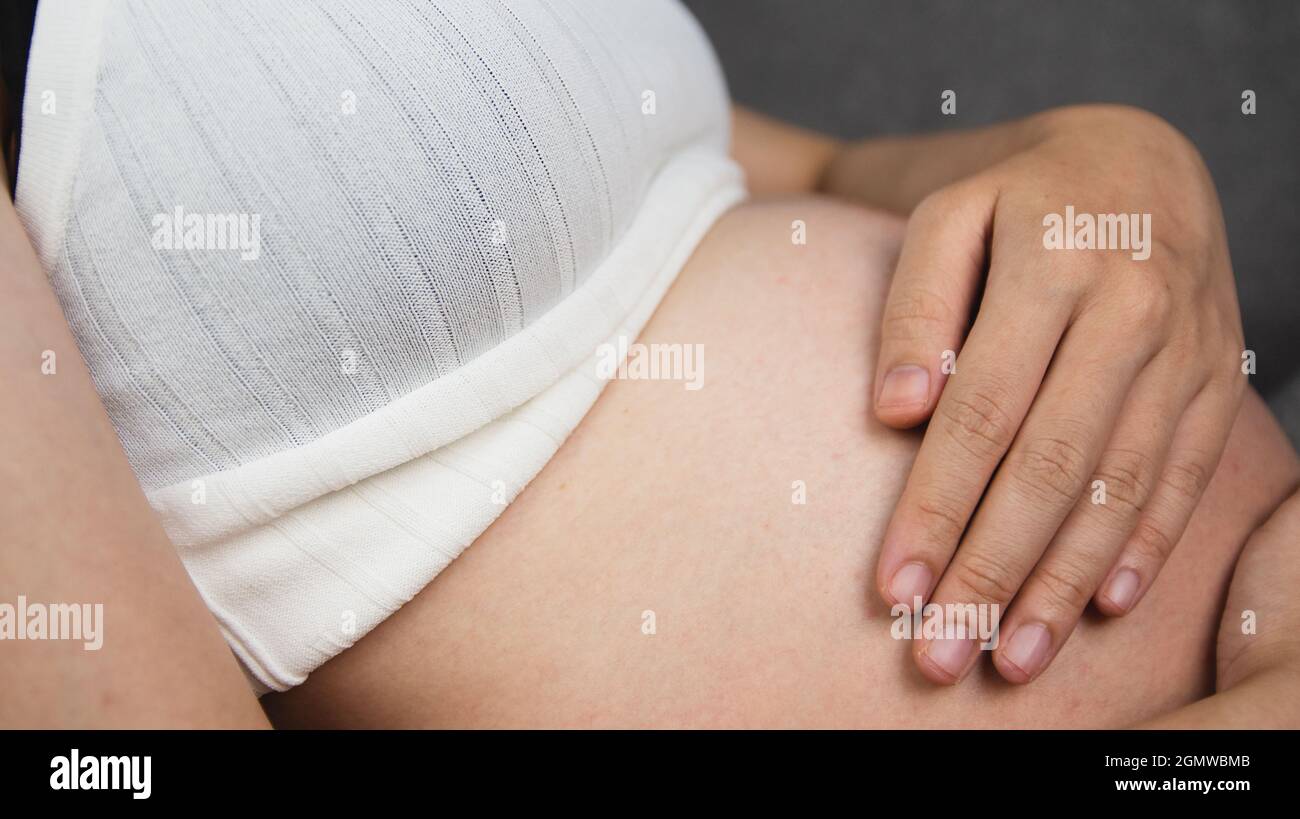 pregnant woman holding her stomach Stock Photo - Alamy