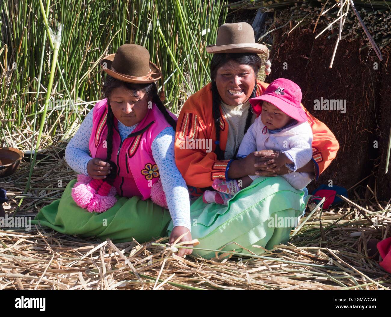 Lake Titicaca, Peru - 17 May 2018; three native people in shot   Situated at 3,812 metres (12,507 ft) elevation, the beautiful, jewel-like Lake Titica Stock Photo