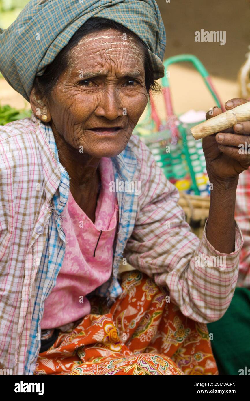 Bagan, Myanmar - 28 January 2013; one old woman in shot. Old tribal woman smoking an outrageous home-grown and hand-rolled cigar in Nyaung - U Market Stock Photo