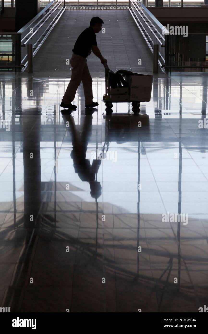 Hong Kong, China - 7 May 2012; one silhouetted man in shot, pushing a trolley. Hong Kong's new Chek Lap Kok airport came into operation in 1988, repla Stock Photo