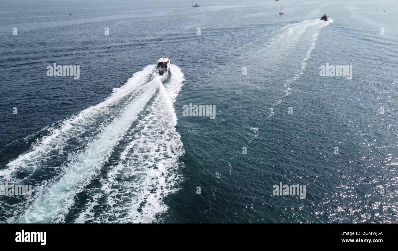 A large white boat is moving at speed on the blue sea water Stock Photo ...