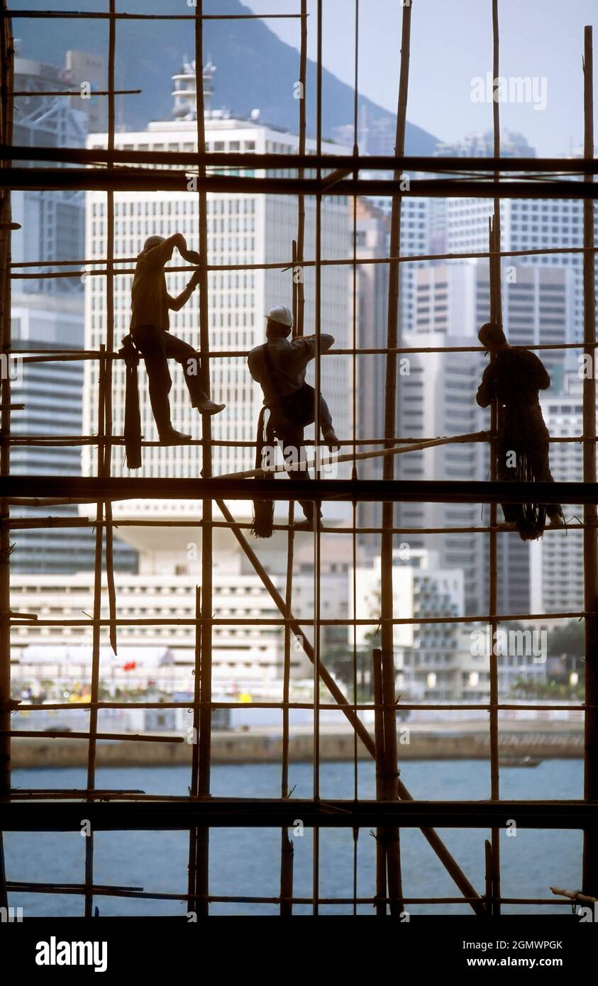 Hong Kong, China - 20 February 2016 Workers silhouetted by the panoramic windows of the Hong Kong Exhibition Centre. Note they still use traditional b Stock Photo