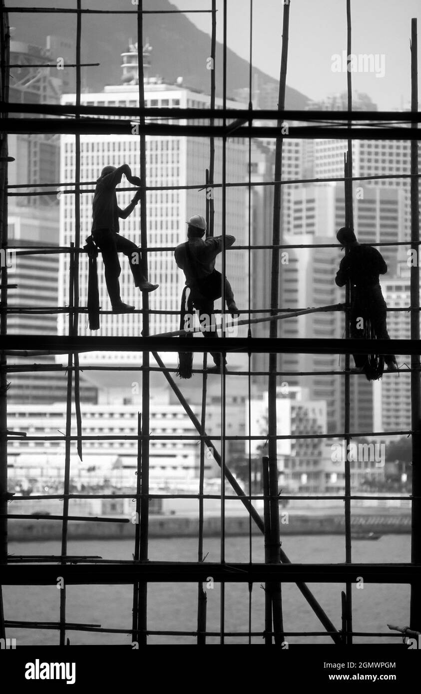 Hong Kong, China - 20 February 2016 Workers silhouetted by the panoramic windows of the Hong Kong Exhibition Centre. Note they still use traditional b Stock Photo