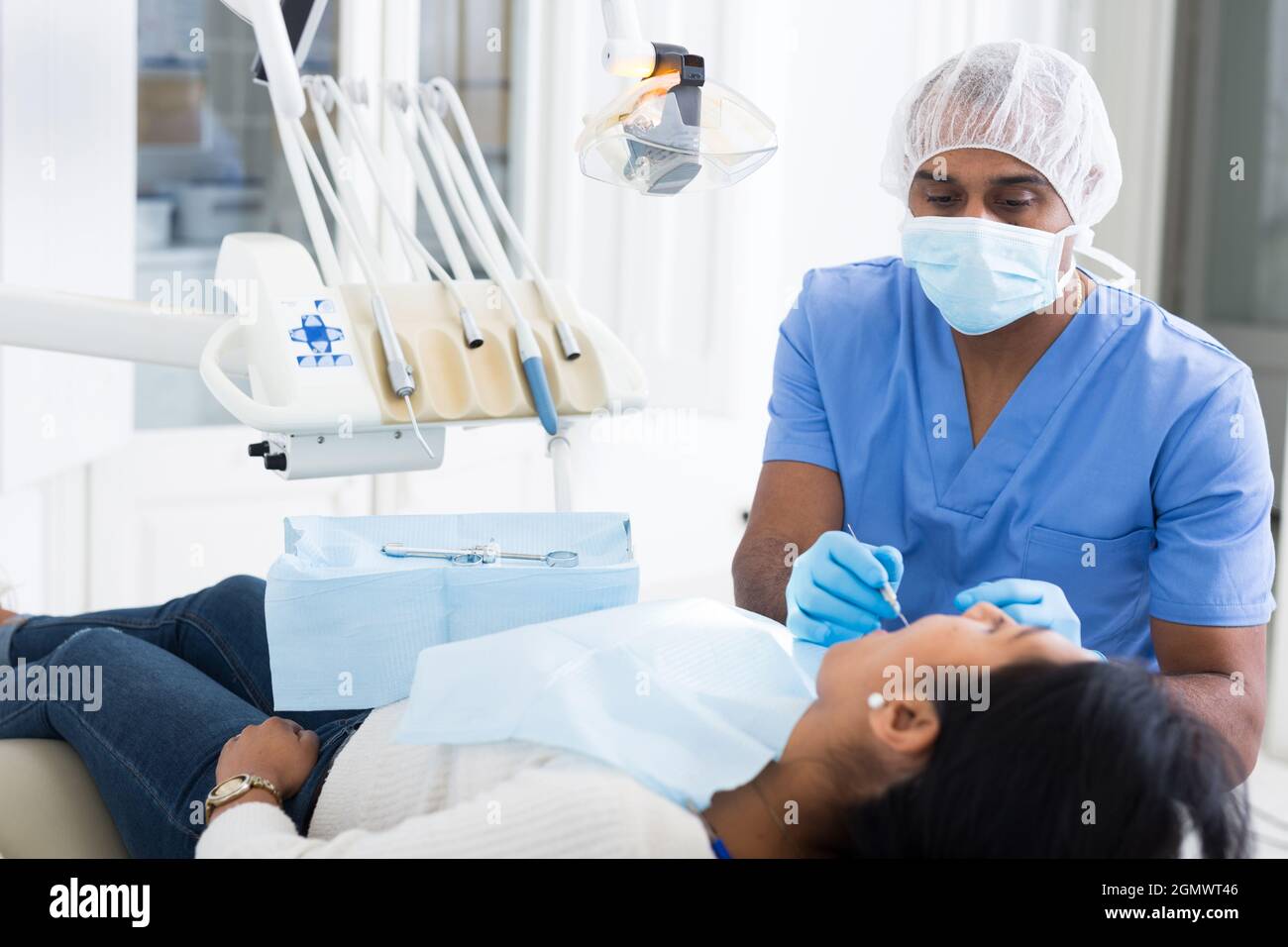 Professional african american dentist performing teeth treatment to