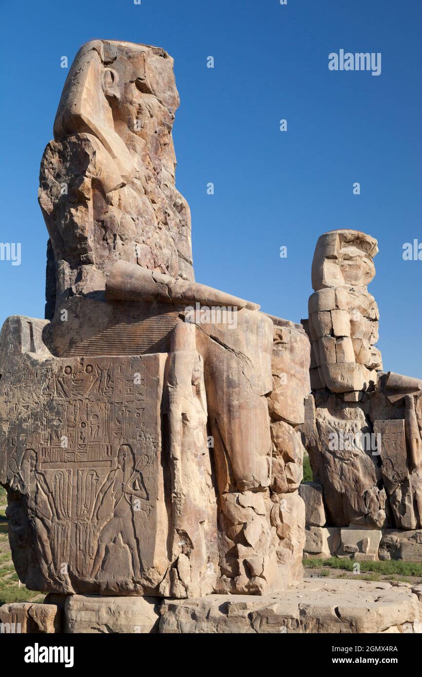 Luxor, Egypt - 30 November 2010; The Colossi of Memnon are two massive stone statues of the Pharaoh Amenhotep III sitting on his hieroglyth-inscribed Stock Photo