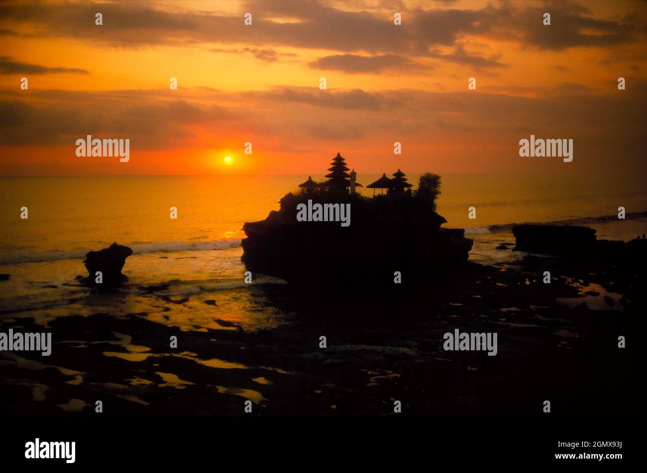 The coastal Hindu Temple of Tanah Lot is famed for its sunset photo opportunities - like this! Its name means Land in the Sea in the Balinese language Stock Photo