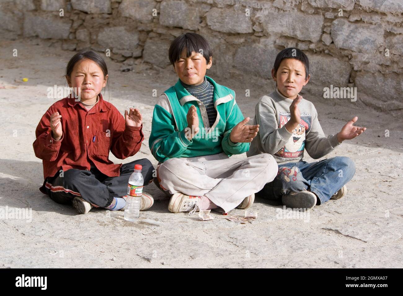 Lhasa, Tibet - 21 October 2006; sitting children, clapping Three youthful faces that are full of character. Despite all of Tibet's travails and strugg Stock Photo