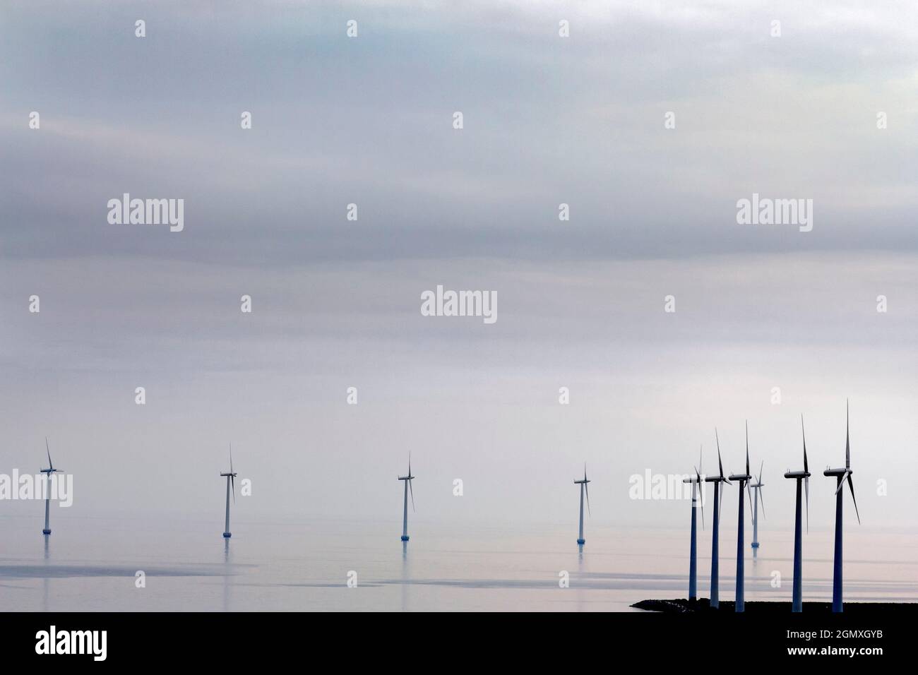 Copenhagen, Denmark - 7 June 2011; Turbines spin in a windfarm in shallow waters outside Copenhagen Harbour, Denmark.Grey clouds loom above the North Stock Photo