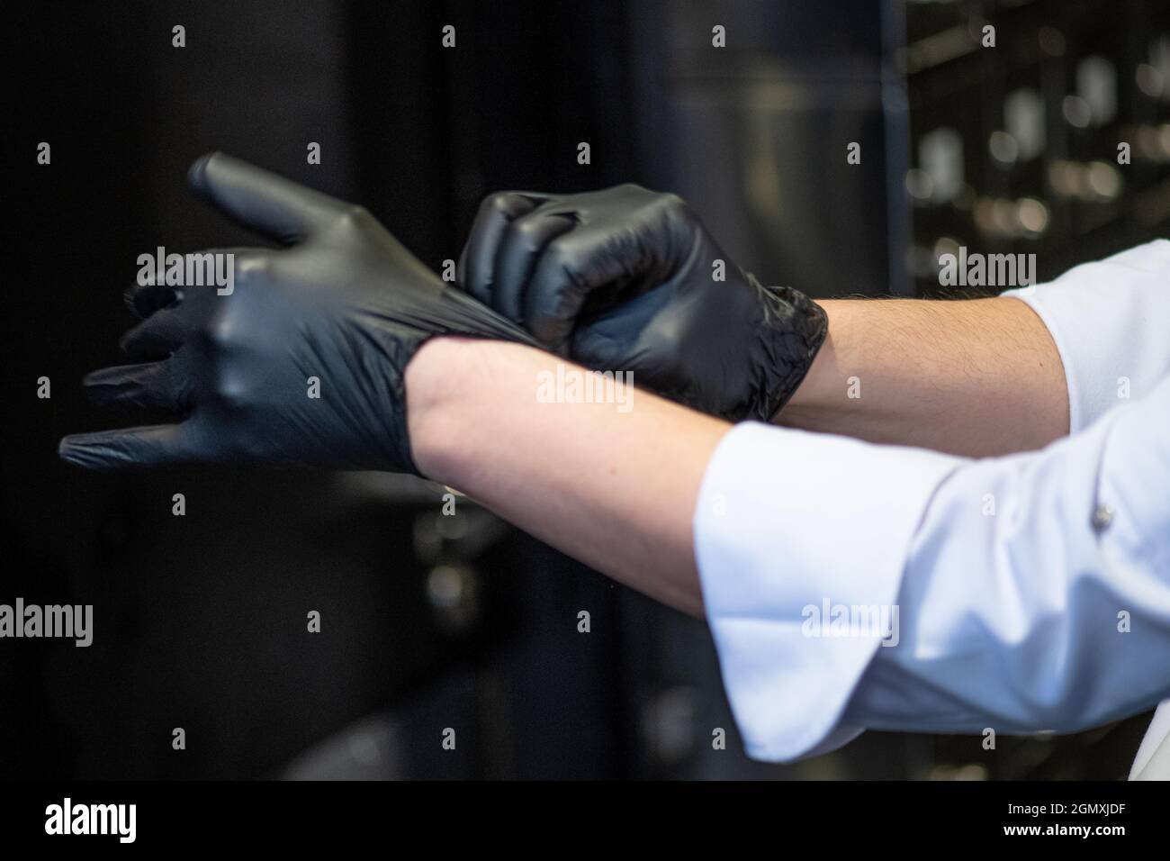 chef wearing plastic gloves. close up of hands with black latex protective gloves. no face Stock Photo
