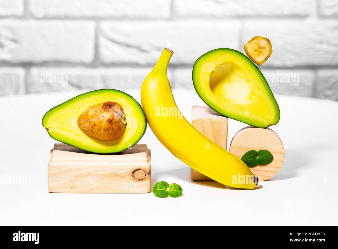 Creative avocado, banana and micro green balance wooden stands and podiums., white background, Equilibrium healthy food. Balanced nutrition concept. Stock Photo