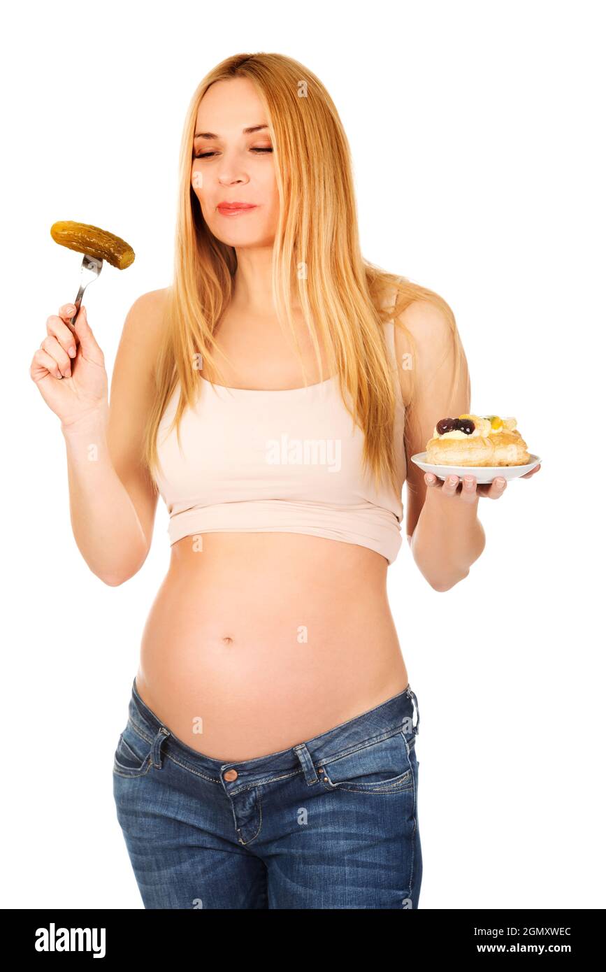 Young pregnant female happily eating sweets Stock Photo