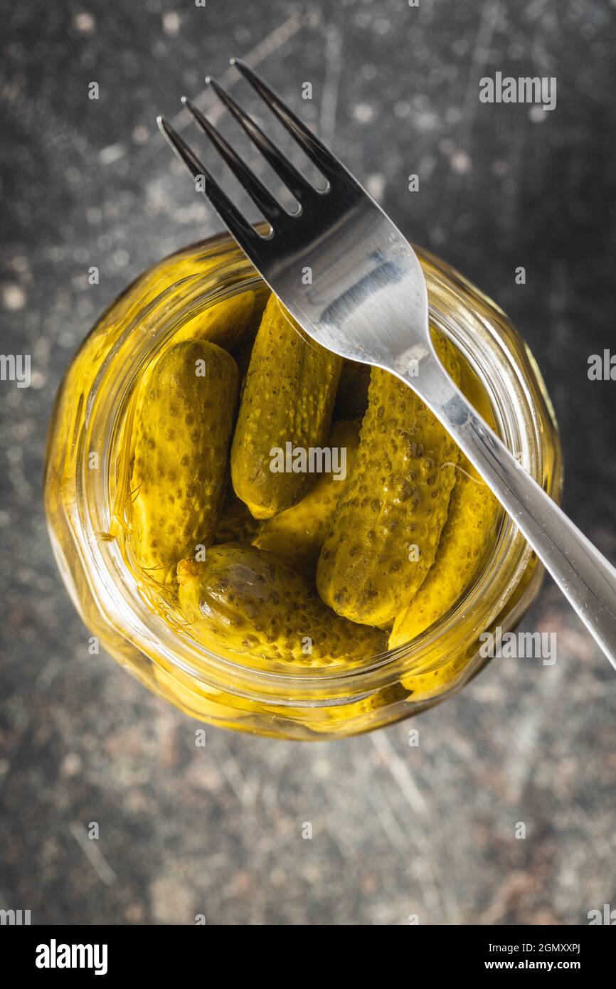 Small pickles. Marinated pickled cucumbers in jar on kitchen table. Top view. Stock Photo