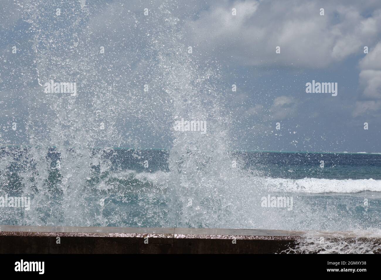 Surf long a wall on the indian ocean against a blue sky with white clouds Stock Photo