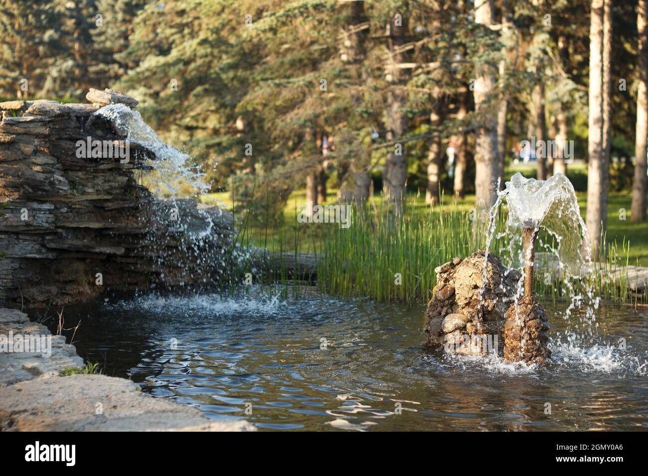 Beautiful pond with fountain in park made in handmade of stones and