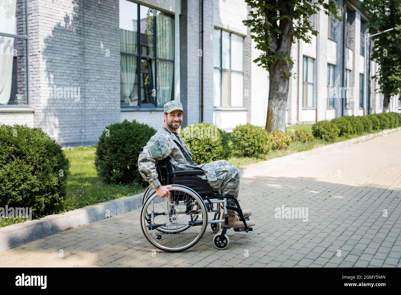 young handicapped veteran in wheelchair smiling on city street Stock Photo