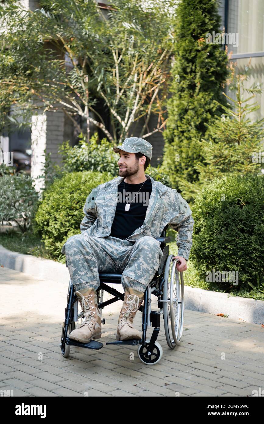 handicapped military man in wheel chair smiling while looking away outdoors Stock Photo