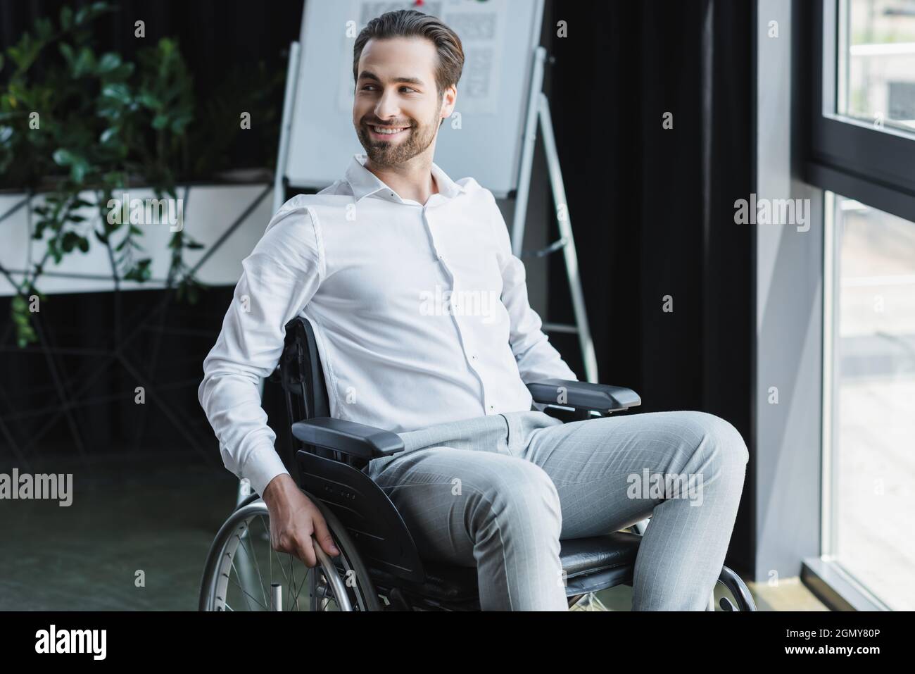 cheerful handicapped businessman looking away and smiling in office Stock Photo