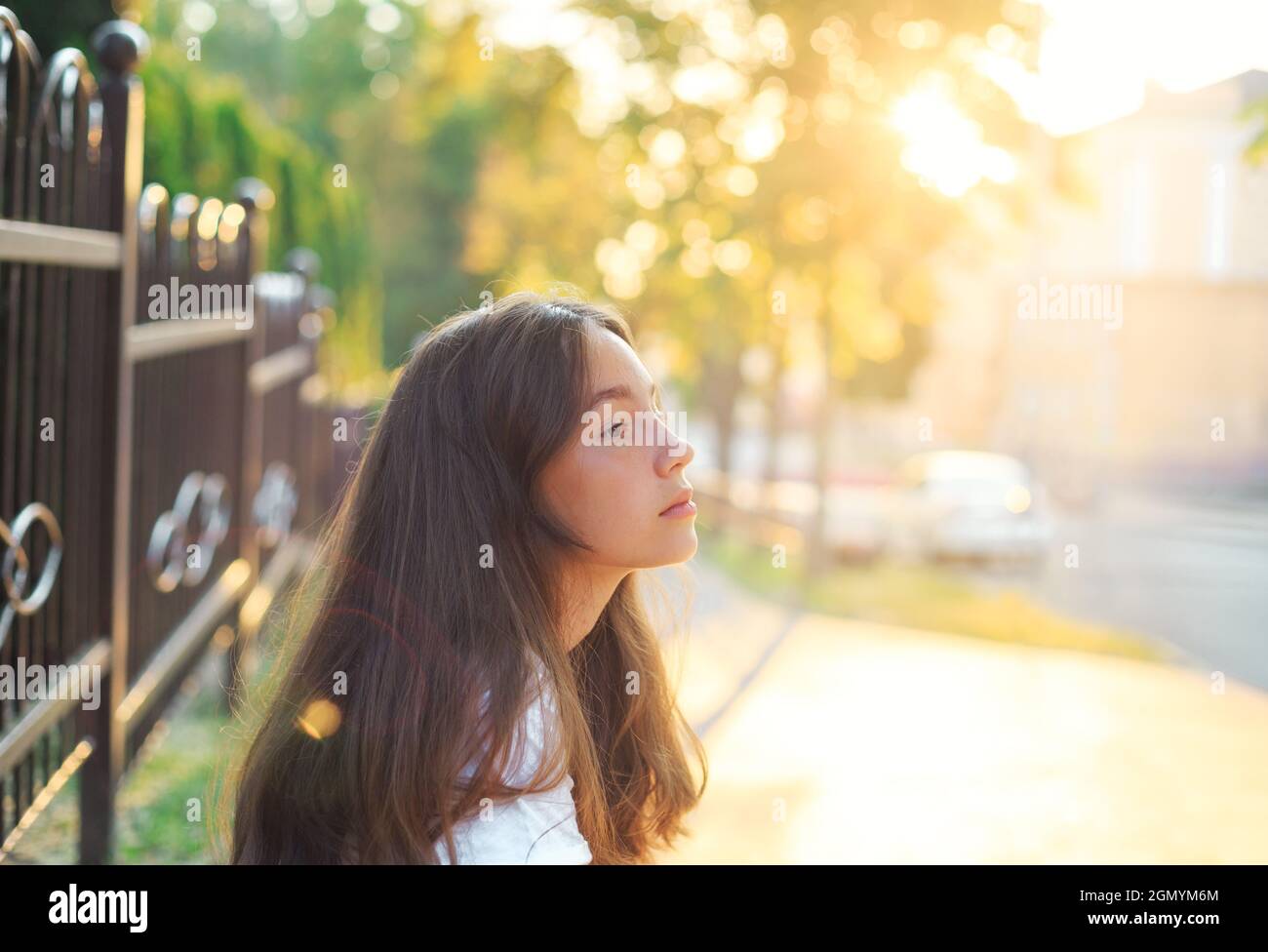 Portrait of a cute teenager girl is dreaming and having fun outdoors at summer evening Stock Photo