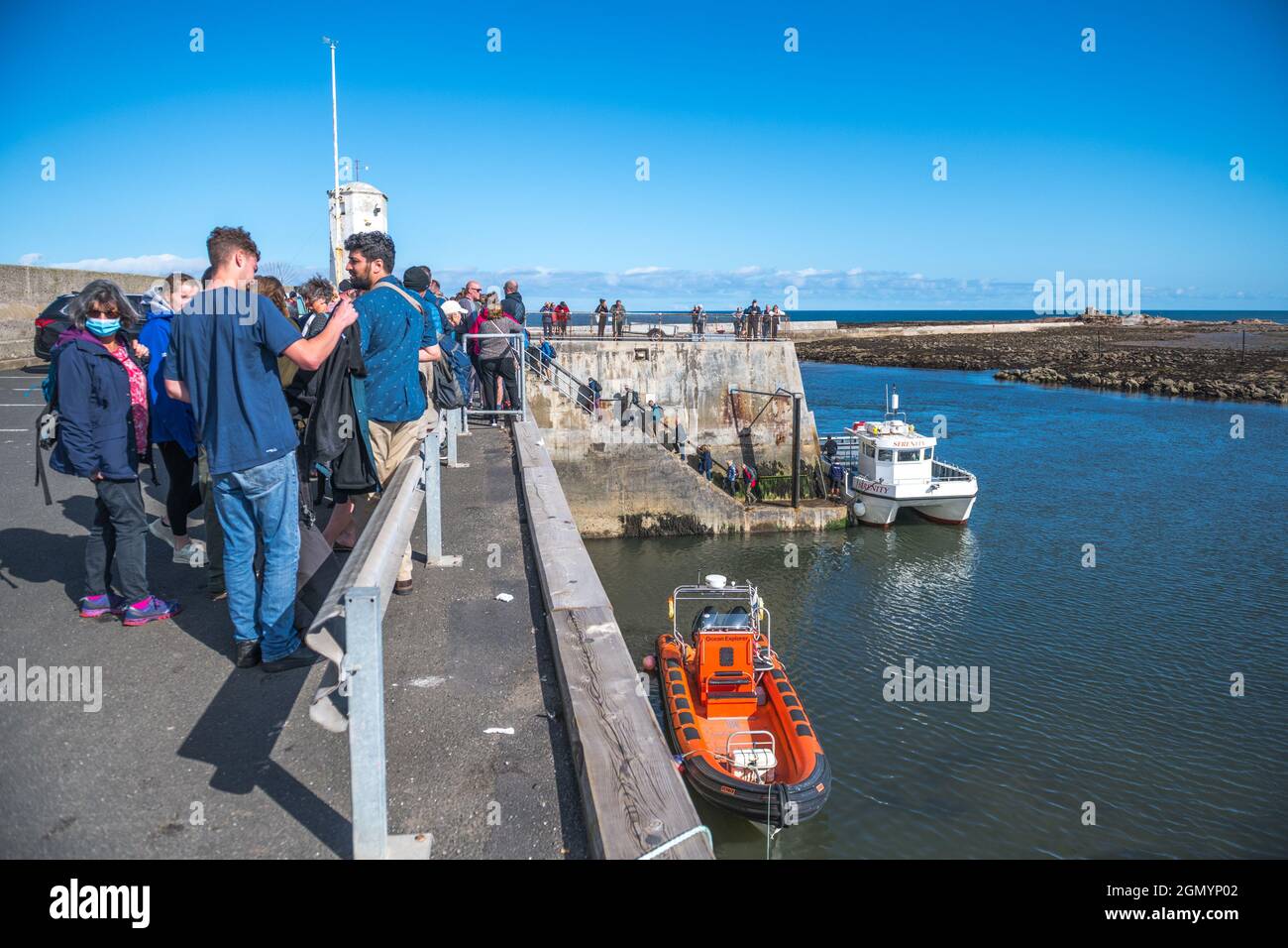 Sight seeing passengers embarking and disembarking after their boat trip to the Farne islands from Seahouses harbour. Stock Photo