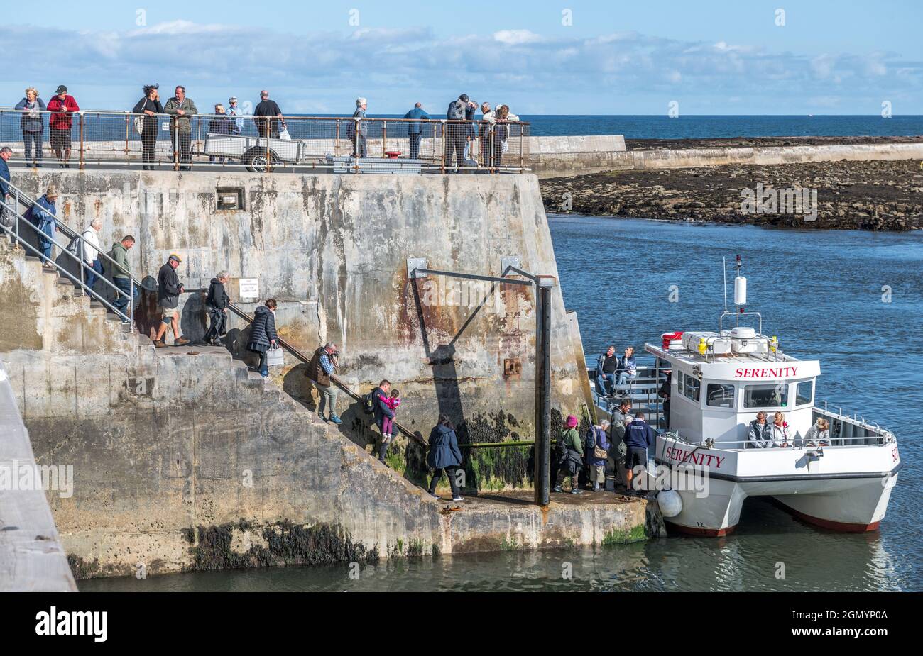 Sight seeing passengers embarking on a their boat trip to the Farne islands from Seahouses harbour. Stock Photo