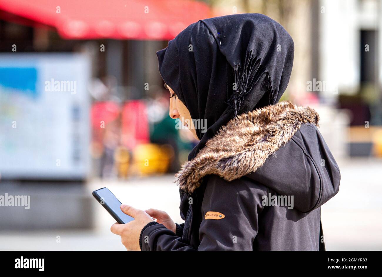 Dundee, Tayside, Scotland, UK. 21st. September 2021. UK weather: A sunny day with a strong cool  breeze across North East Scotland, temperatures reaching 17°C. A Muslim woman spending the day out enjoying the cool sunny weather whilst texting messages on her mobile phone in Dundee city centre. Credit: Dundee Photographics/Alamy Live News Stock Photo