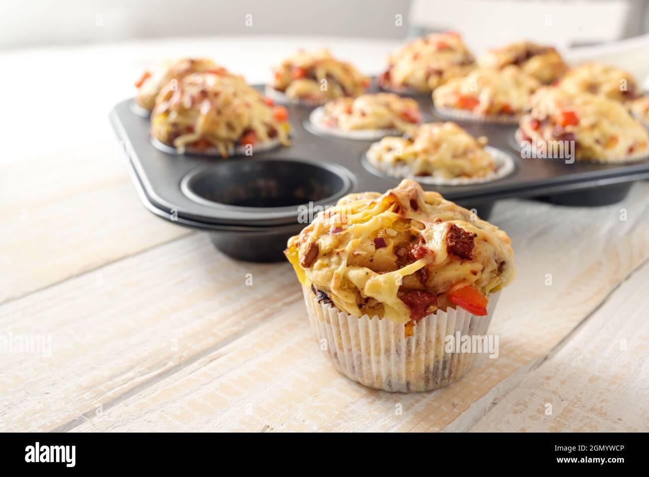 Tasty baked pizza muffins as finger food for a party from yeast dough, tomatoes, vegetables, sausage and cheese on a wooden table, copy space, selecte Stock Photo