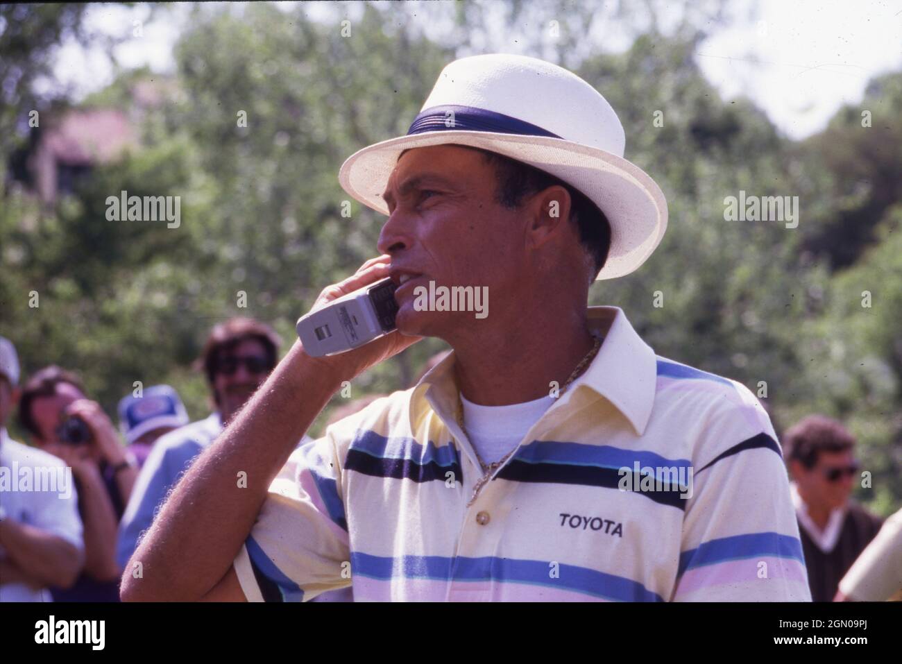 Austin Texas USA, 1989: Professional golfer Chi Chi Rodriguez talks on a cellphone with a bulky battery while on the course at the Legends of Golf tournament for senior players. ©Bob Daemmrich Stock Photo