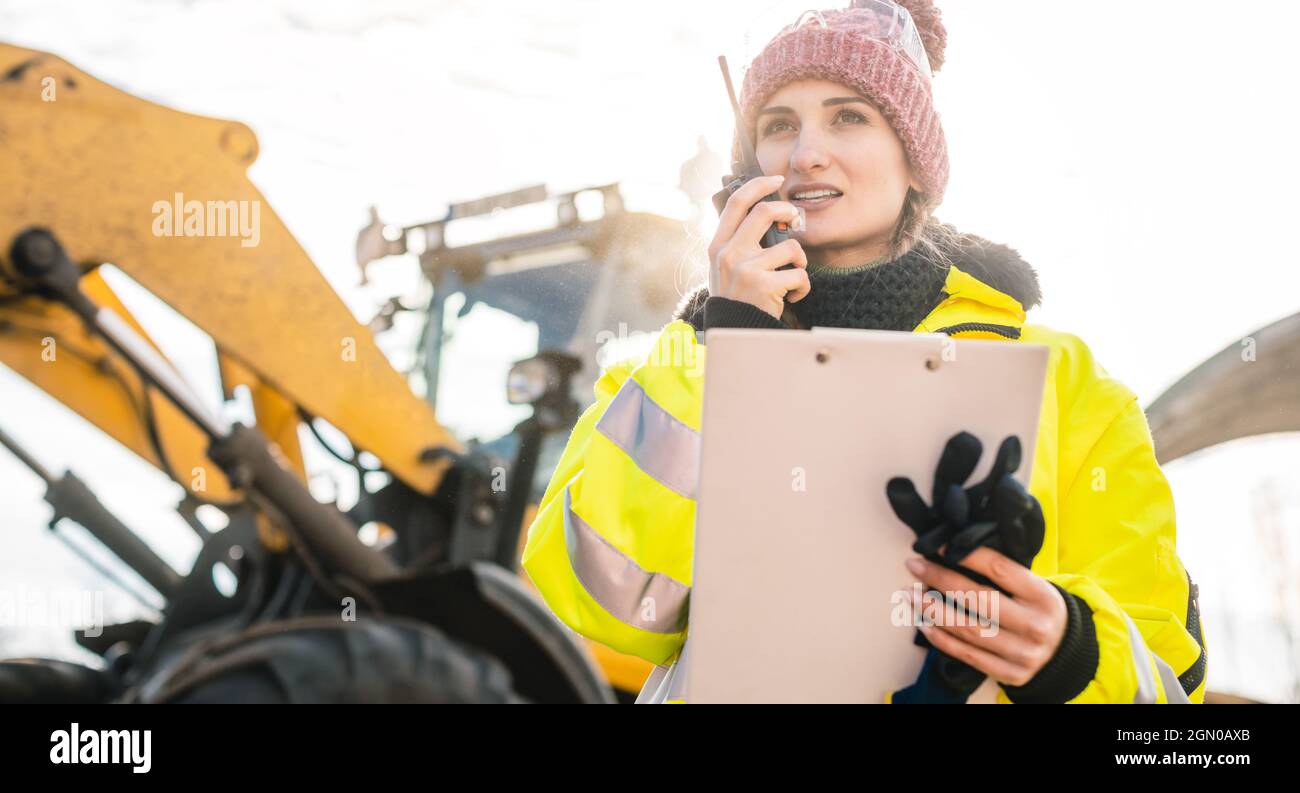 Woman with walkie talky on compost facility dispatching deliveries Stock Photo