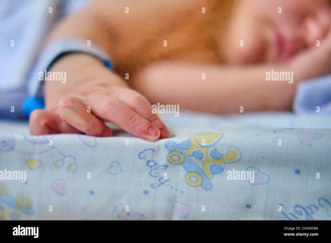 Hand newborn baby with a maternity hospital bracelet on his arm is