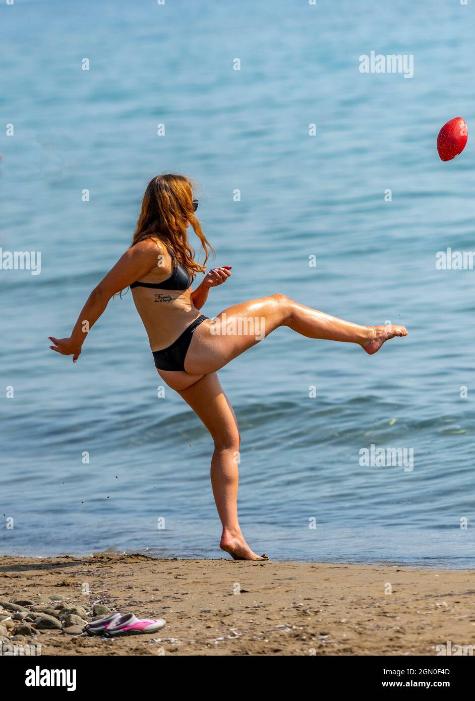 Young fit woman on beach,Greek holiday, fit and healthy woman in bikini,  woman kicking rugby ballon beach, woman playing ballon beach, young lady  ball Stock Photo - Alamy