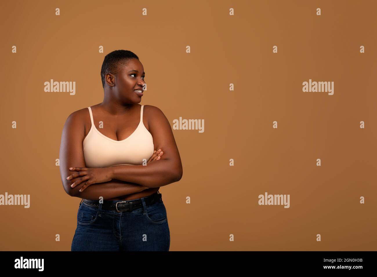 https://c8.alamy.com/comp/2GN0H3B/portrait-of-smiling-young-curvy-african-american-woman-standing-with-folded-hands-looking-wearing-bra-and-jeans-looking-aside-at-free-copy-space-isola-2GN0H3B.jpg