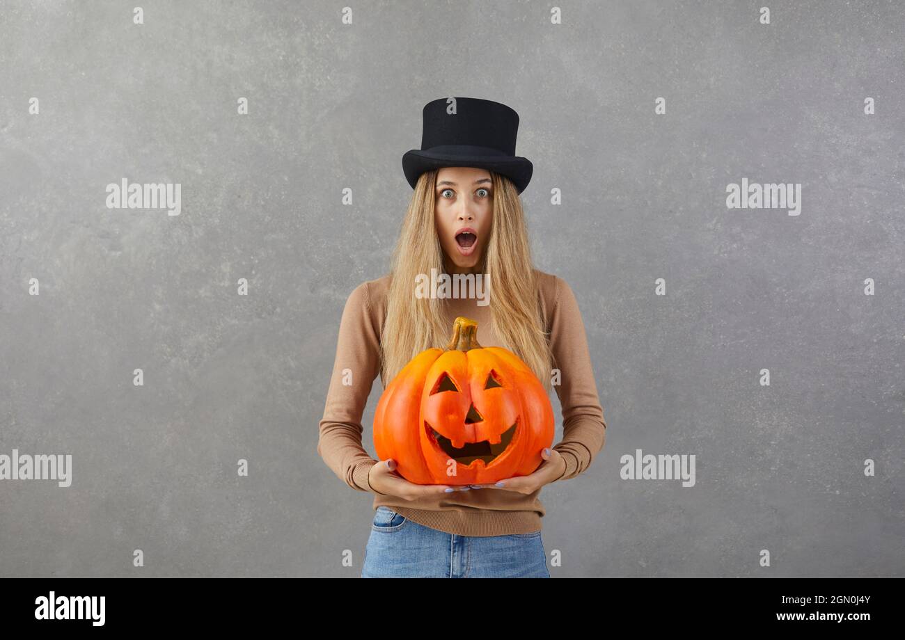 Woman with Halloween pumpkin looking at camera with shocked, scared face expression Stock Photo