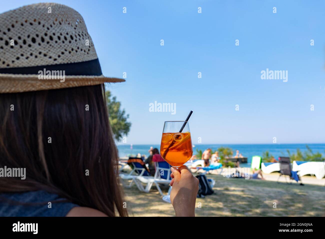 Woman drinking a long drink cocktail on the beach in Piran Slovenia Stock Photo