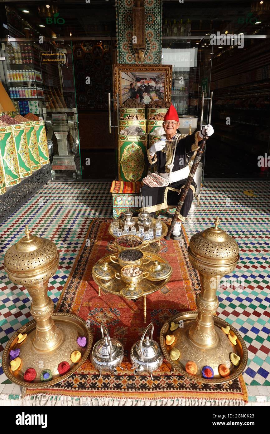 Traditionally dressed Moroccan offering tea outside a spice store main square Marrakesh Medina quarter, Morocco Stock Photo