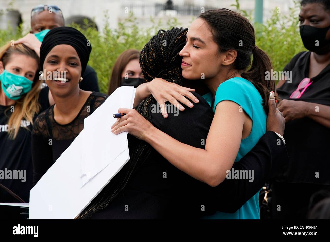 U.S. Representatives Cori Bush (D-MO) and Alexandria Ocasio-Cortez (D-NY)  embrace as U.S. Representative Ilhan Omar (D-MN) looks on before the start  of a news conference discussing the introduction of rent legislation outside